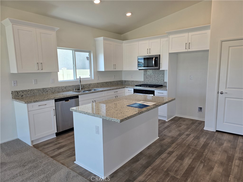 a kitchen with granite countertop a sink stove and refrigerator