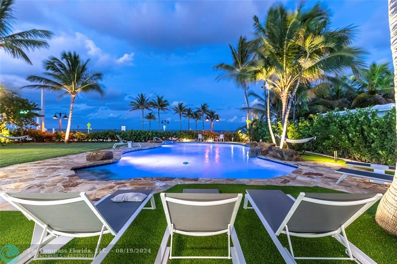 a view of a swimming pool with lawn chairs under an umbrella