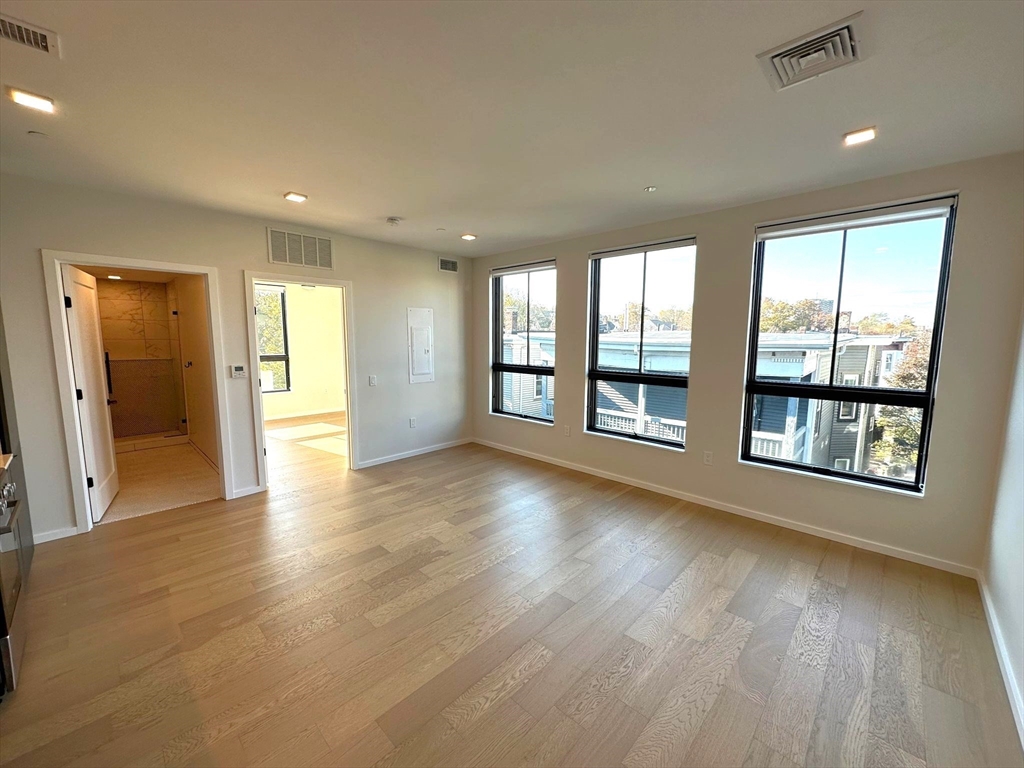 a view of an empty room with a window and wooden floor