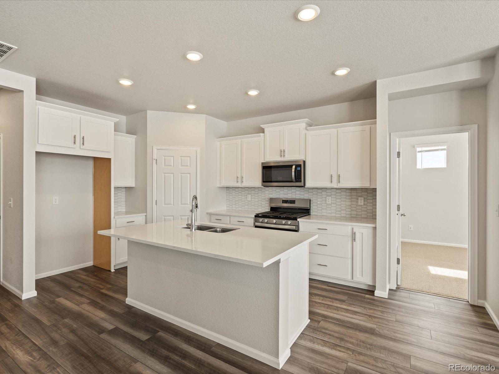 a kitchen with stainless steel appliances a stove top oven a sink and a refrigerator