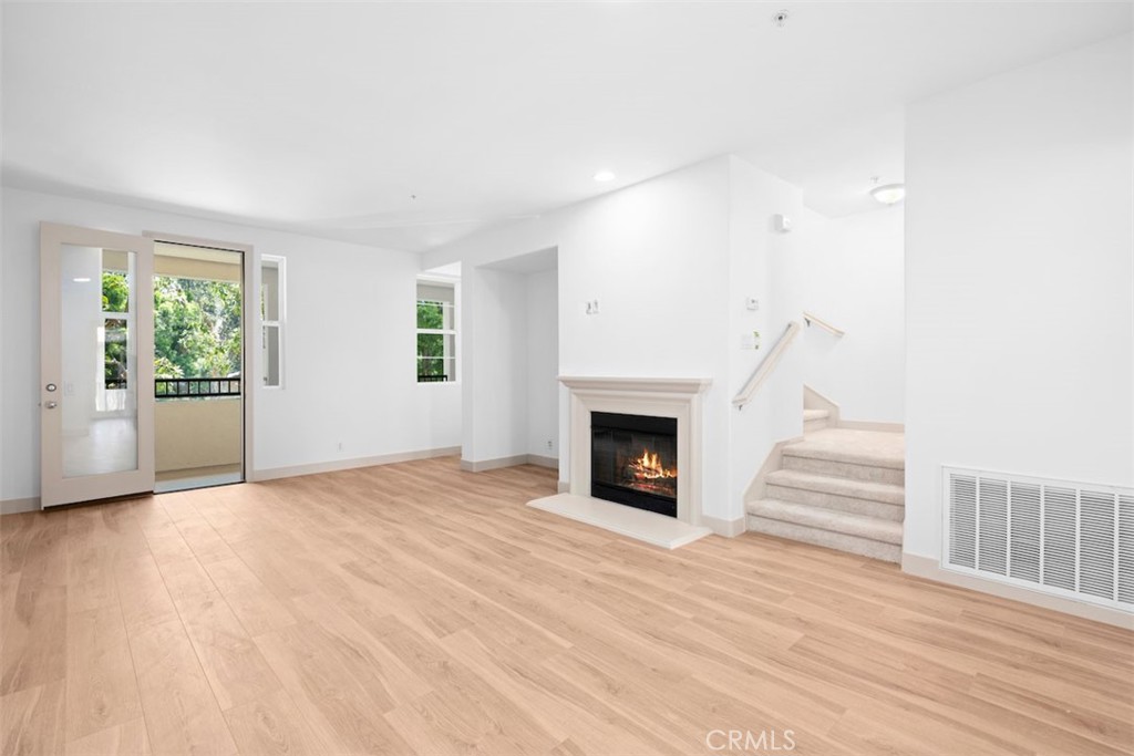 a view of empty room with wooden floor and fireplace