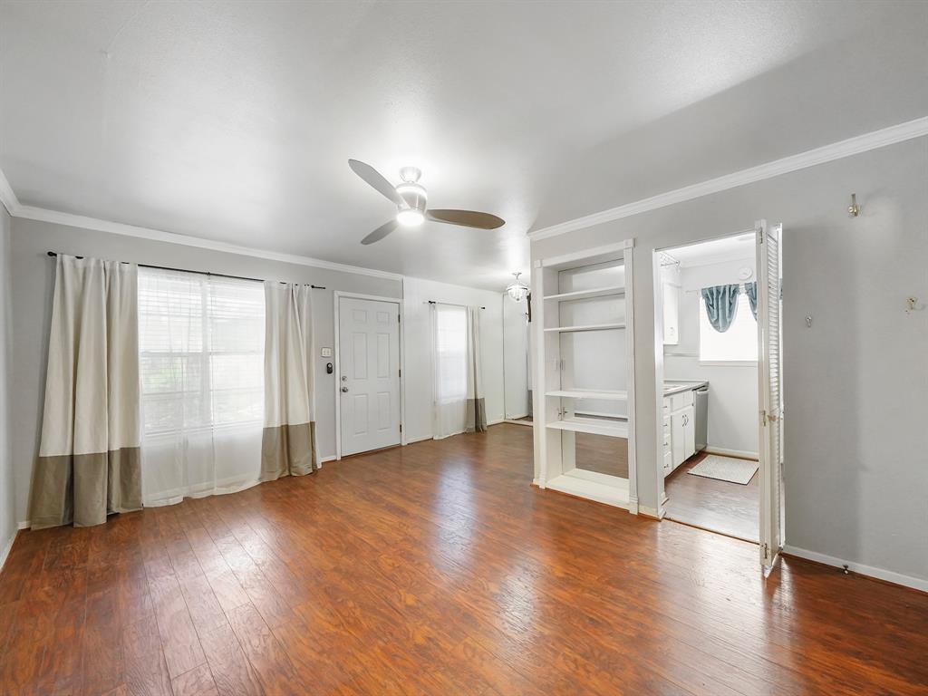 an empty room with wooden floor cabinet and windows