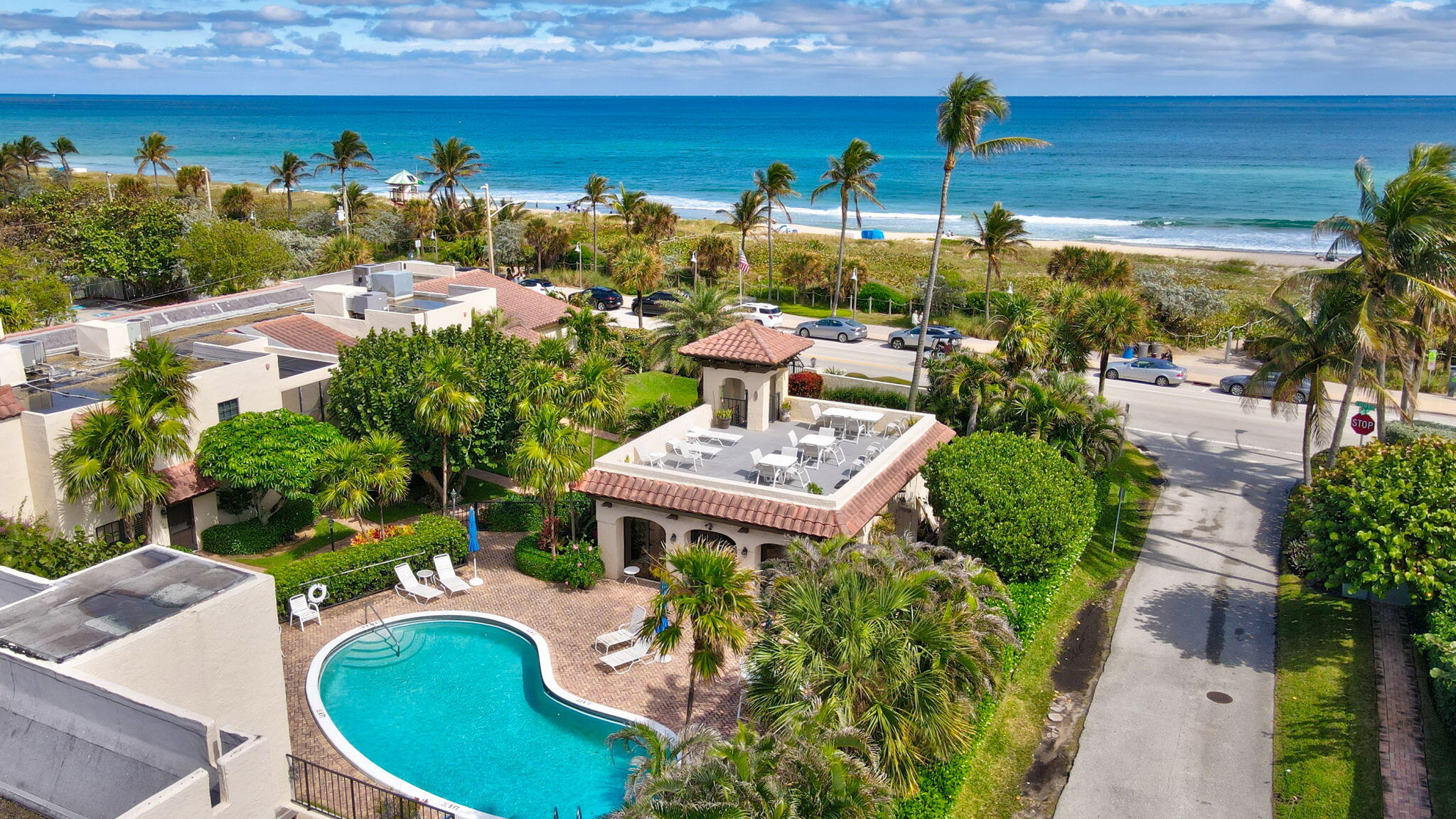 a view of a swimming pool with lawn chairs potted plants