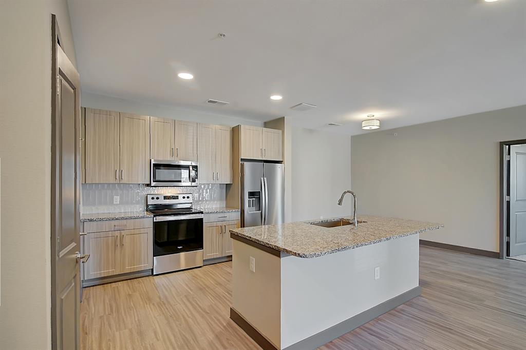 a kitchen with stainless steel appliances granite countertop a sink a stove a refrigerator and cabinets