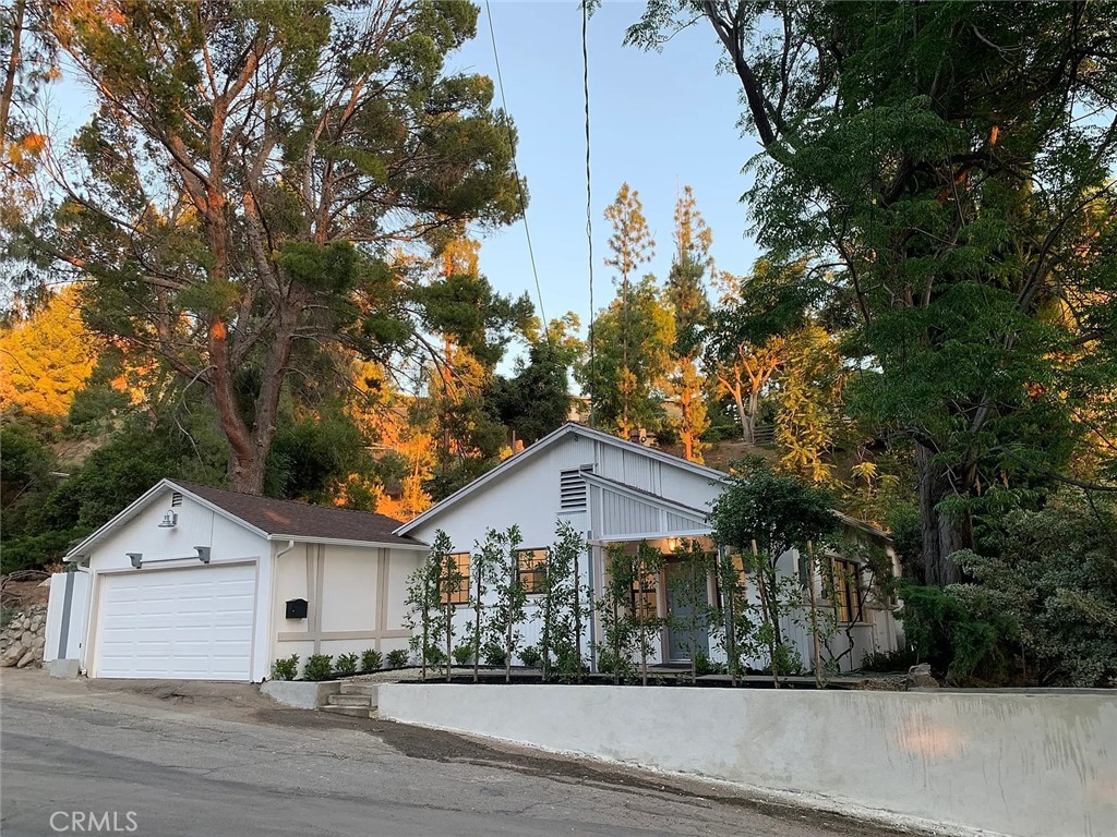 a view of a white house next to a yard with large trees