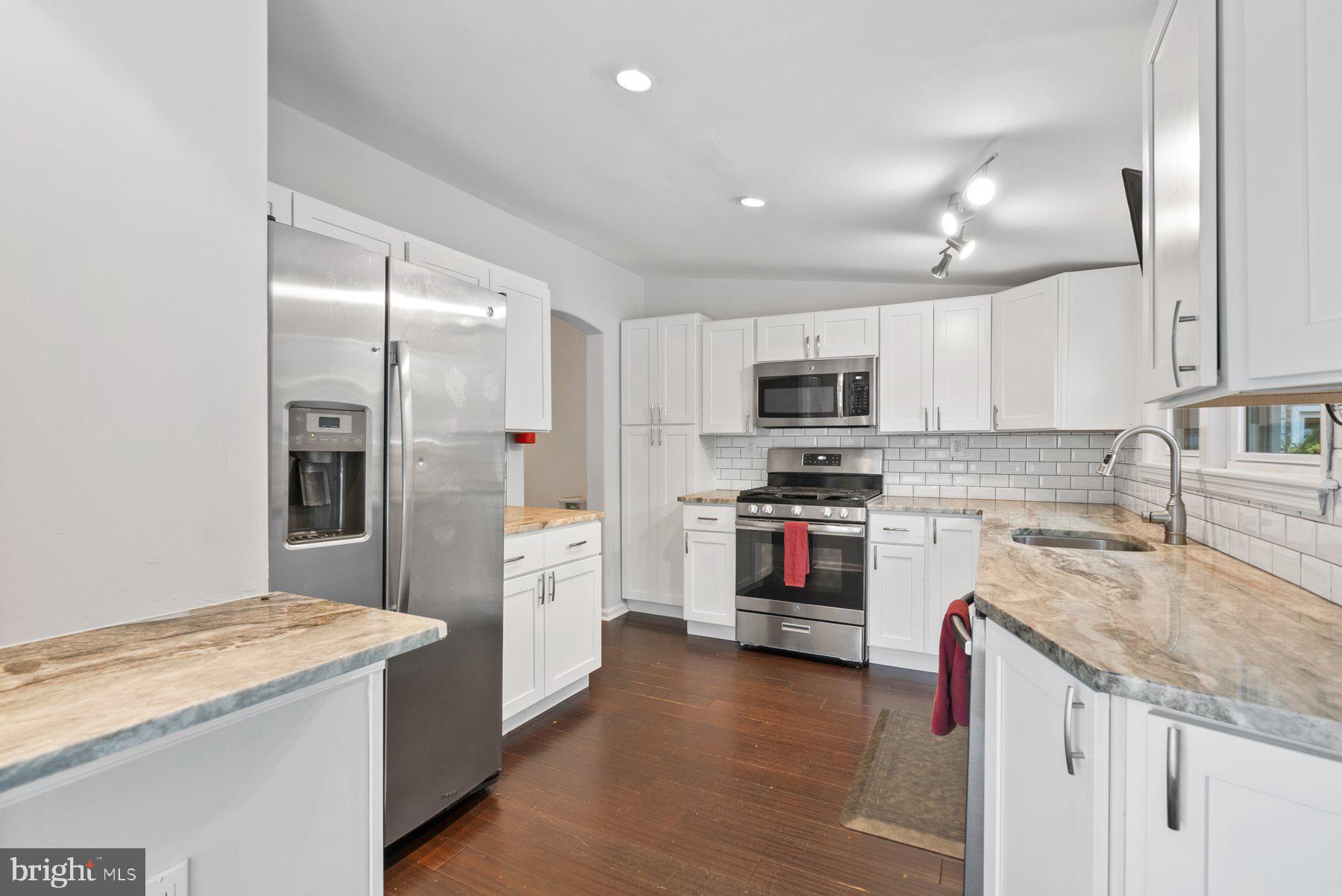 a kitchen with granite countertop white cabinets and stainless steel appliances