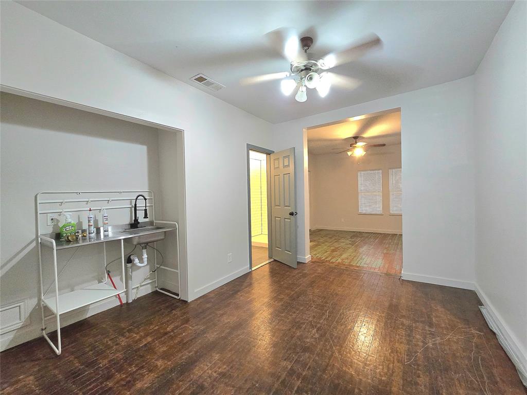 a view of an empty room and chandelier fan wooden floor and a kitchen