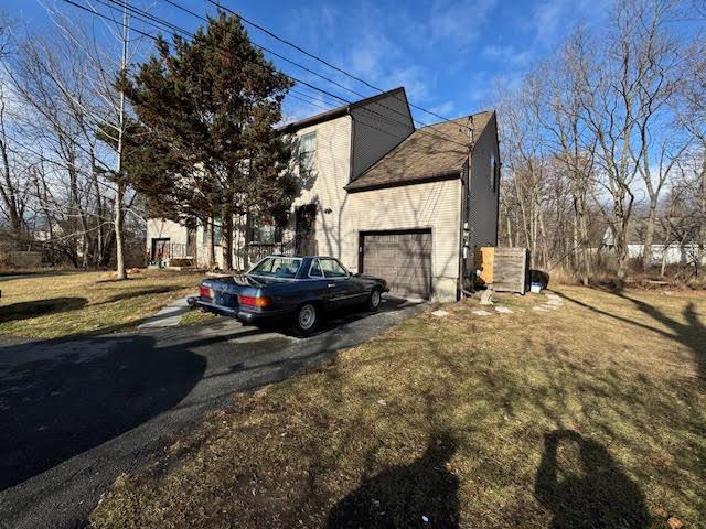 View of home's exterior featuring a garage and a yard.