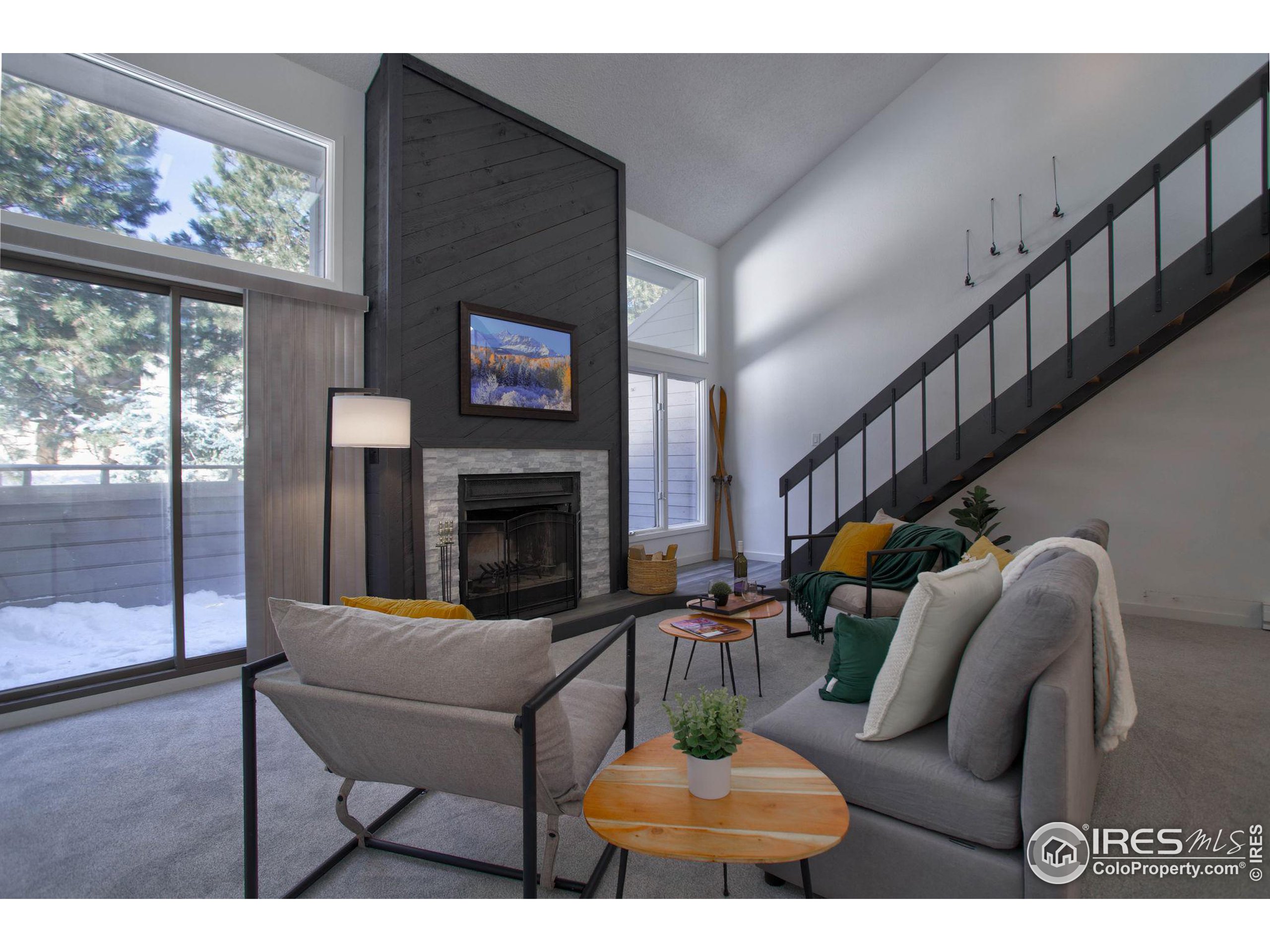 a living room with furniture a fireplace and a floor to ceiling window