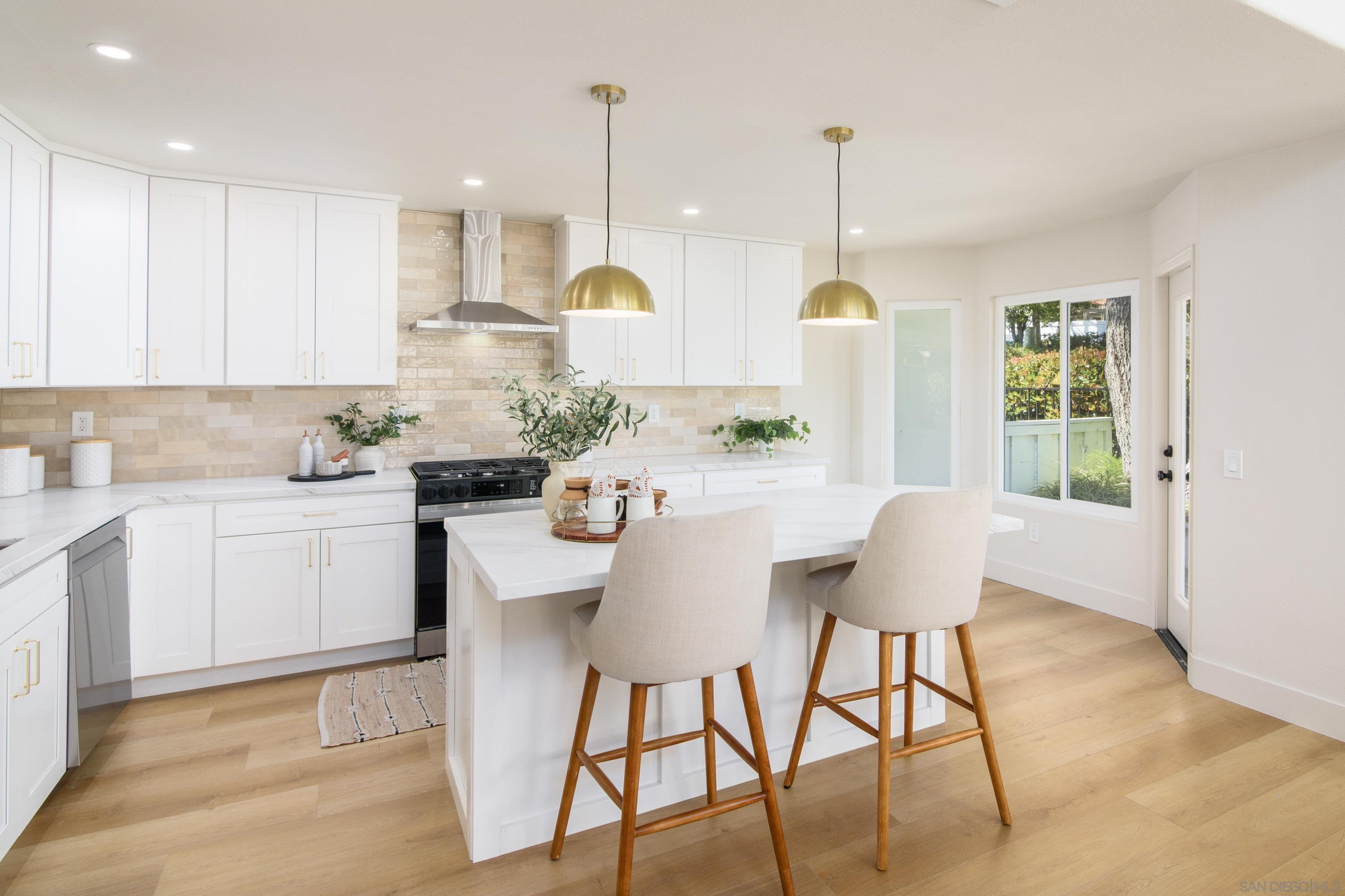 a kitchen with kitchen island granite countertop a table chairs a sink dishwasher window and cabinets