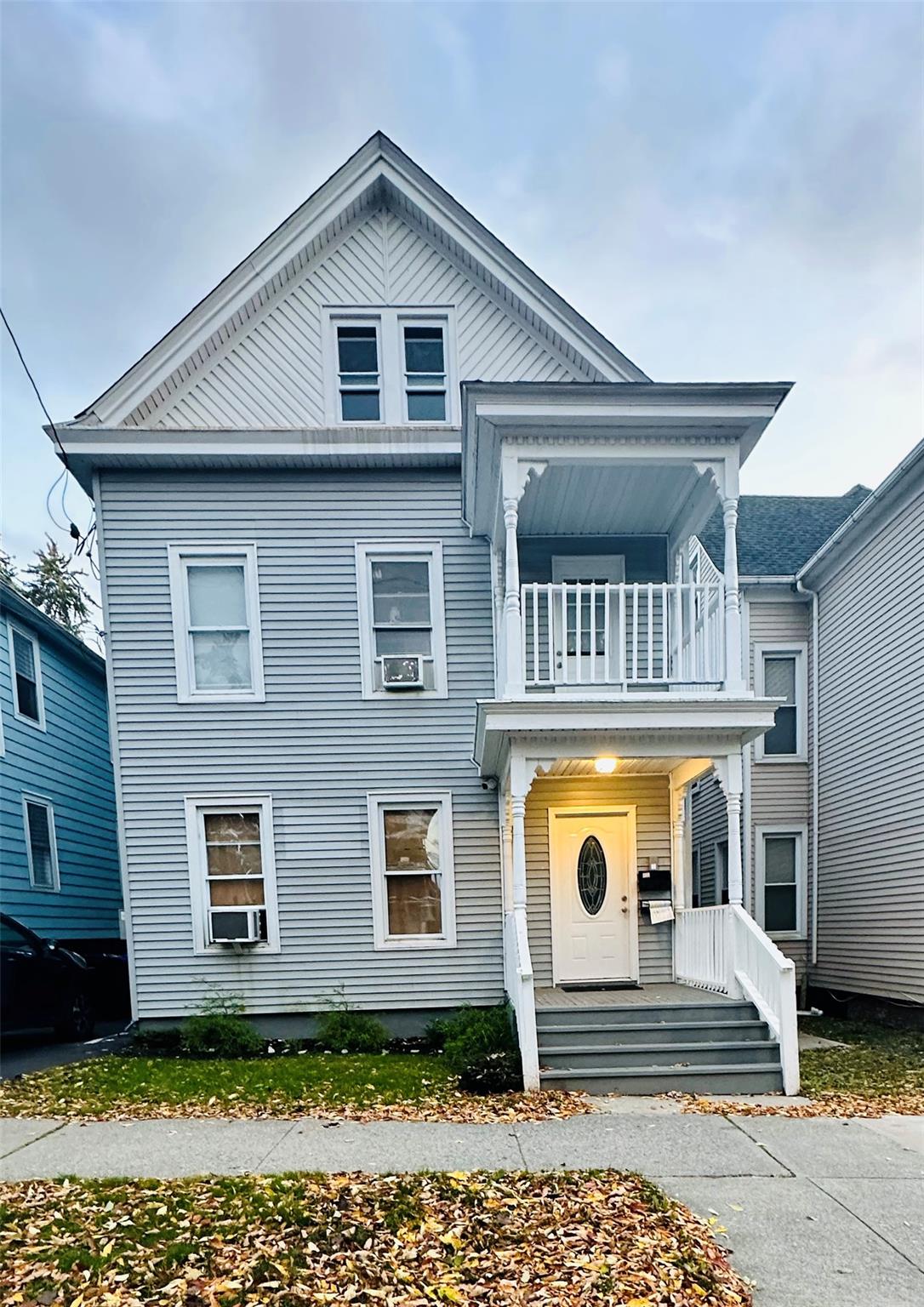 View of front of property featuring covered porch, cooling unit, and a balcony