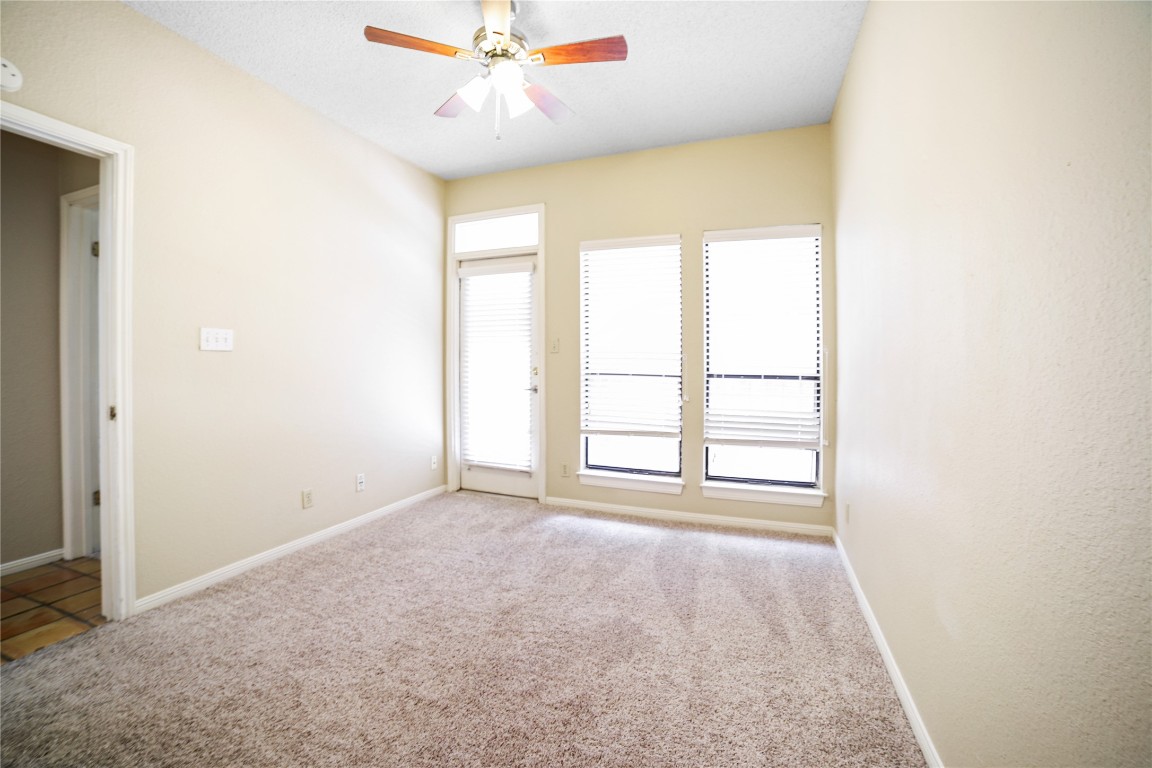 an empty room with windows and ceiling fan