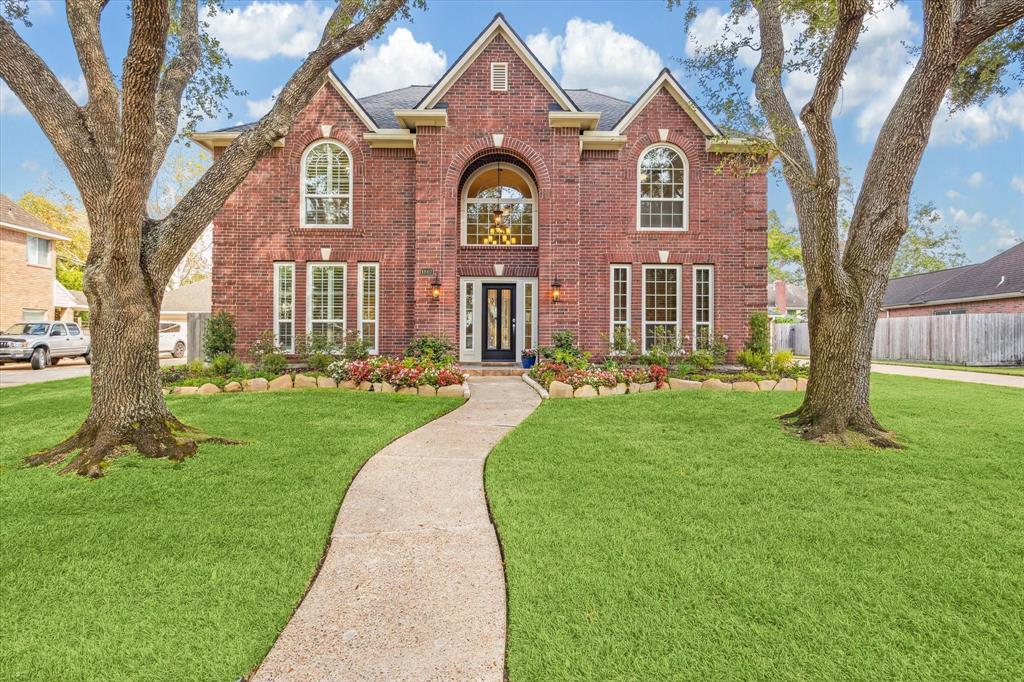 a front view of a house with a garden and trees