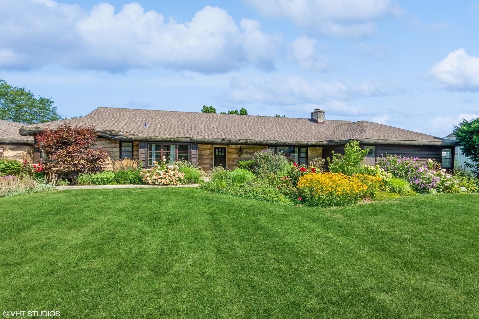 a view of a house with a big yard potted plants and large tree