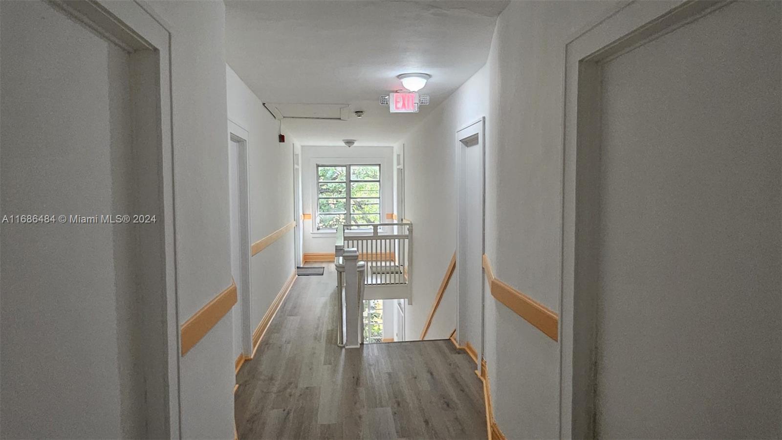 a view of a hallway with wooden floor and a living room