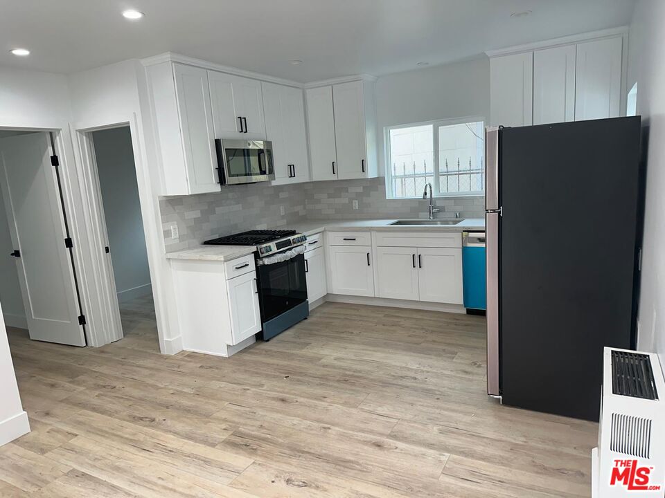 a kitchen with granite countertop a refrigerator stove and sink