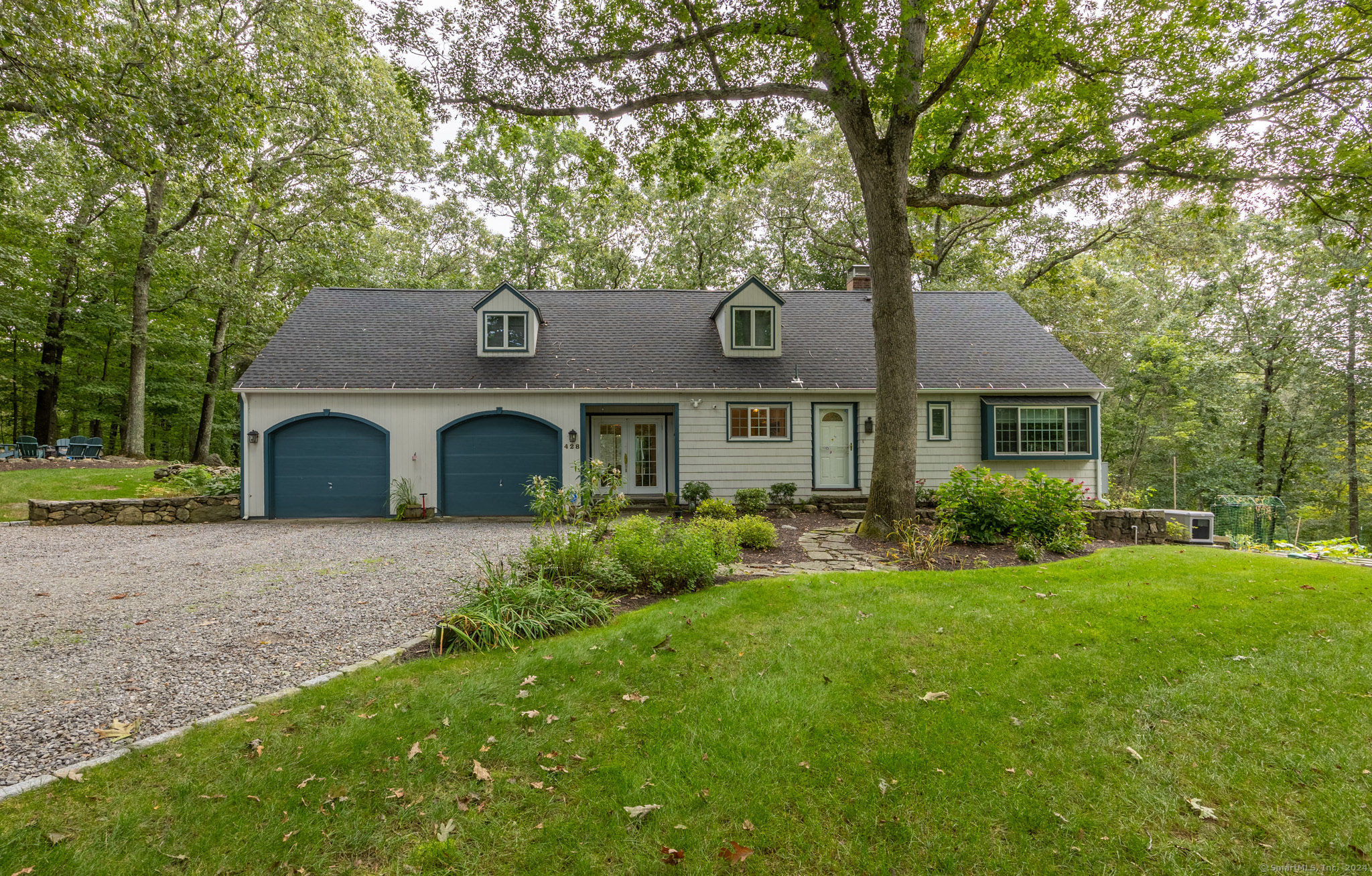 a front view of a house with garden and trees