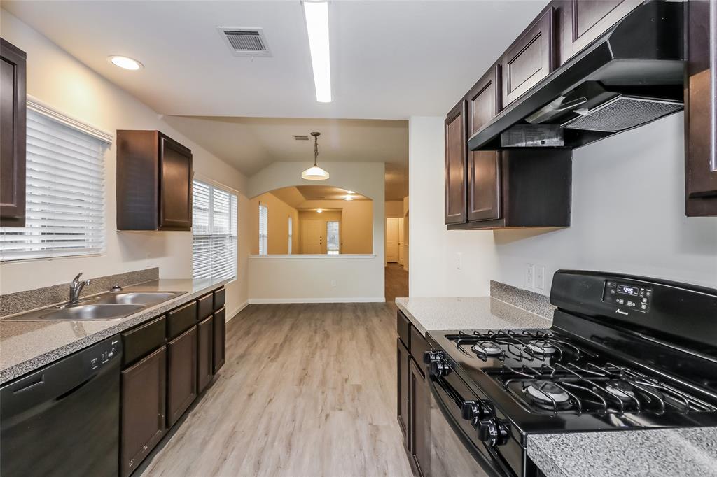 a kitchen with granite countertop stainless steel appliances a sink a stove top oven a counter space and cabinets