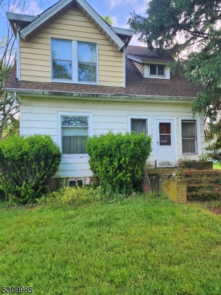 a view of a house with a yard and a large tree