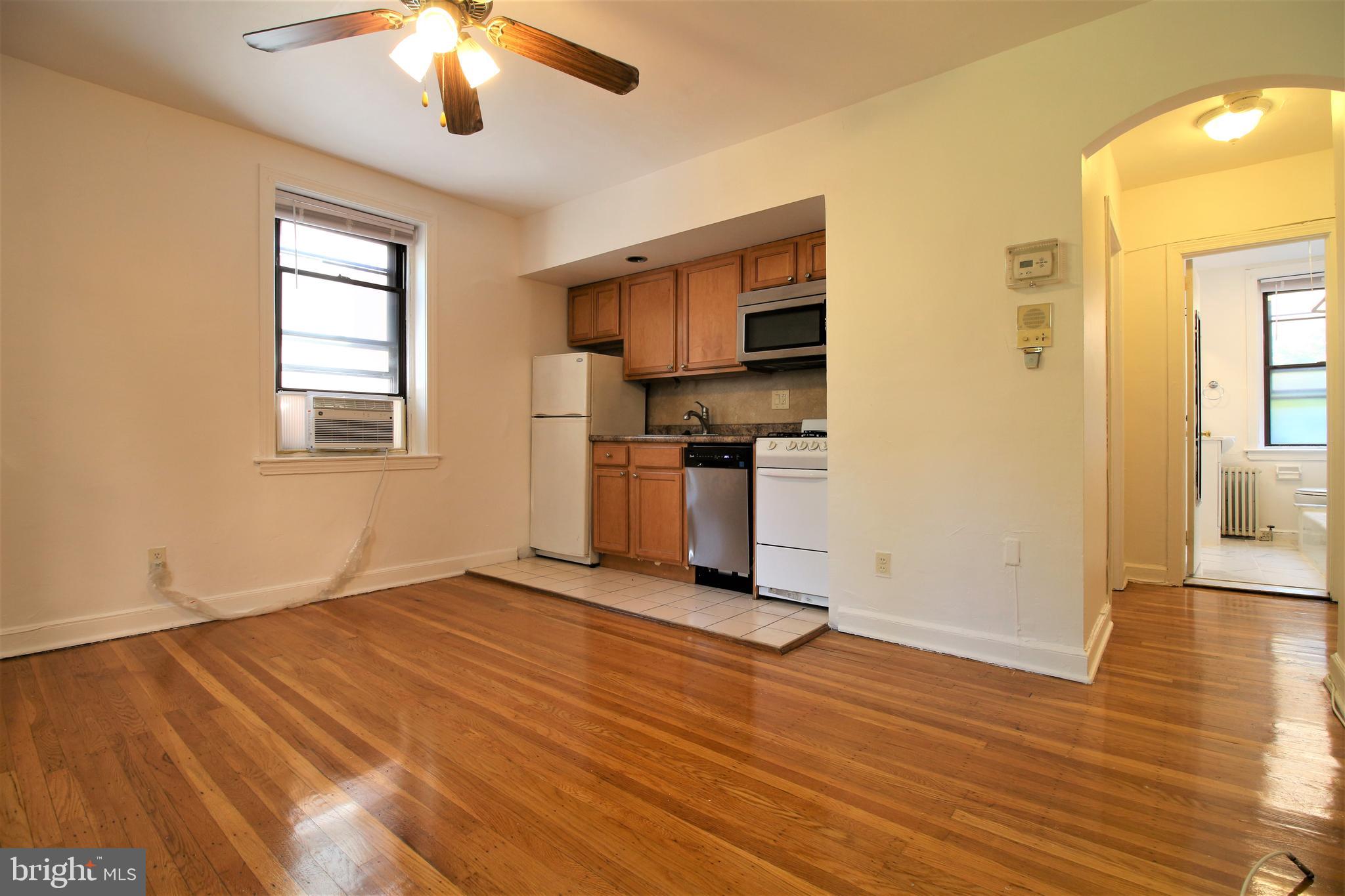 a view of a room with wooden floor a ceiling fan and windows