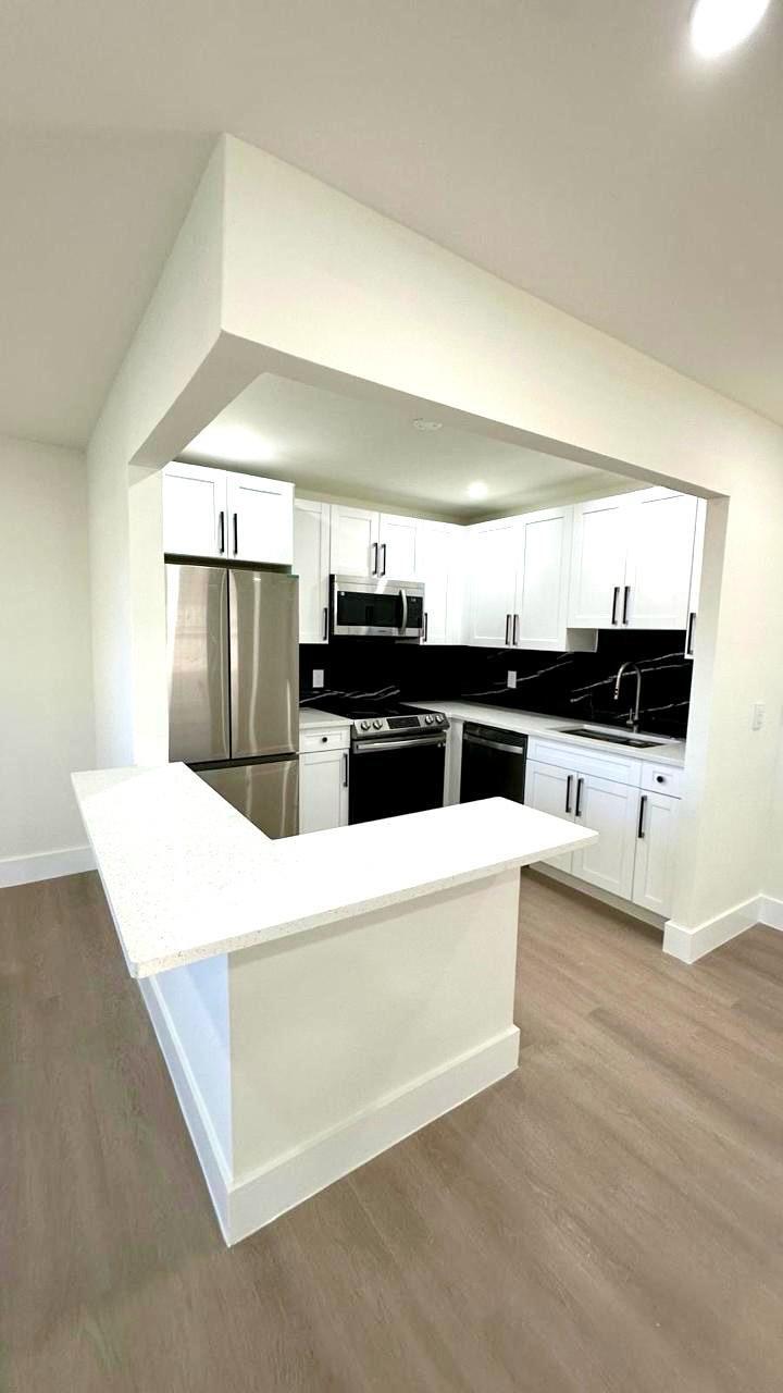 a large white kitchen with stainless steel appliances a refrigerator and a stove