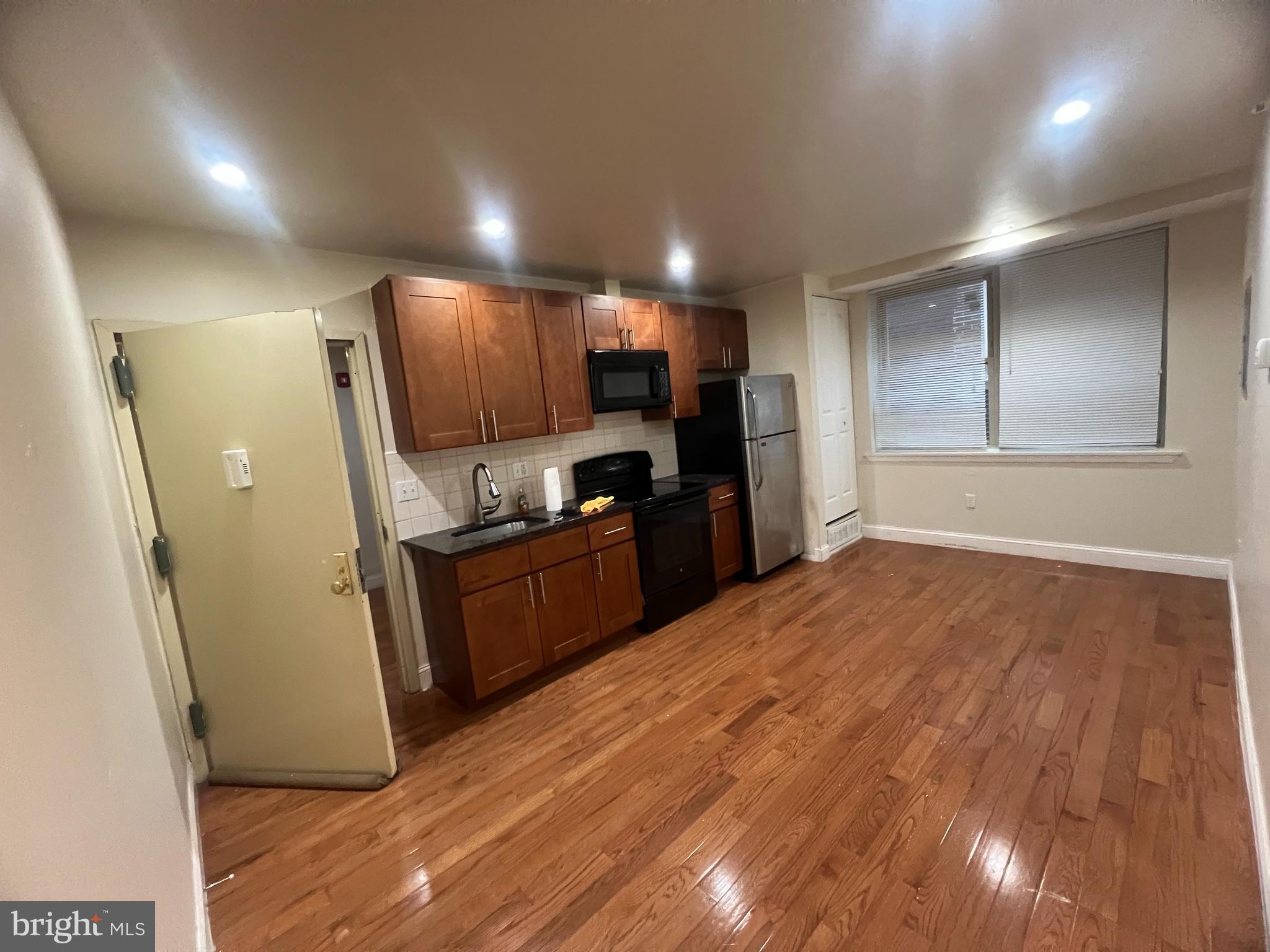 a kitchen with stainless steel appliances kitchen island granite countertop a refrigerator and a sink