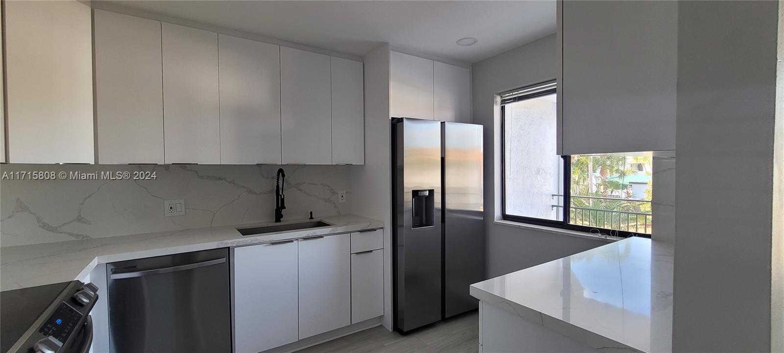 a kitchen with stainless steel appliances granite countertop a sink refrigerator and cabinets