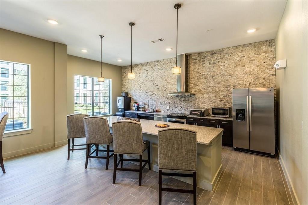 a kitchen with stainless steel appliances granite countertop a kitchen island a stove a refrigerator a sink a dining table and chairs with wooden floor