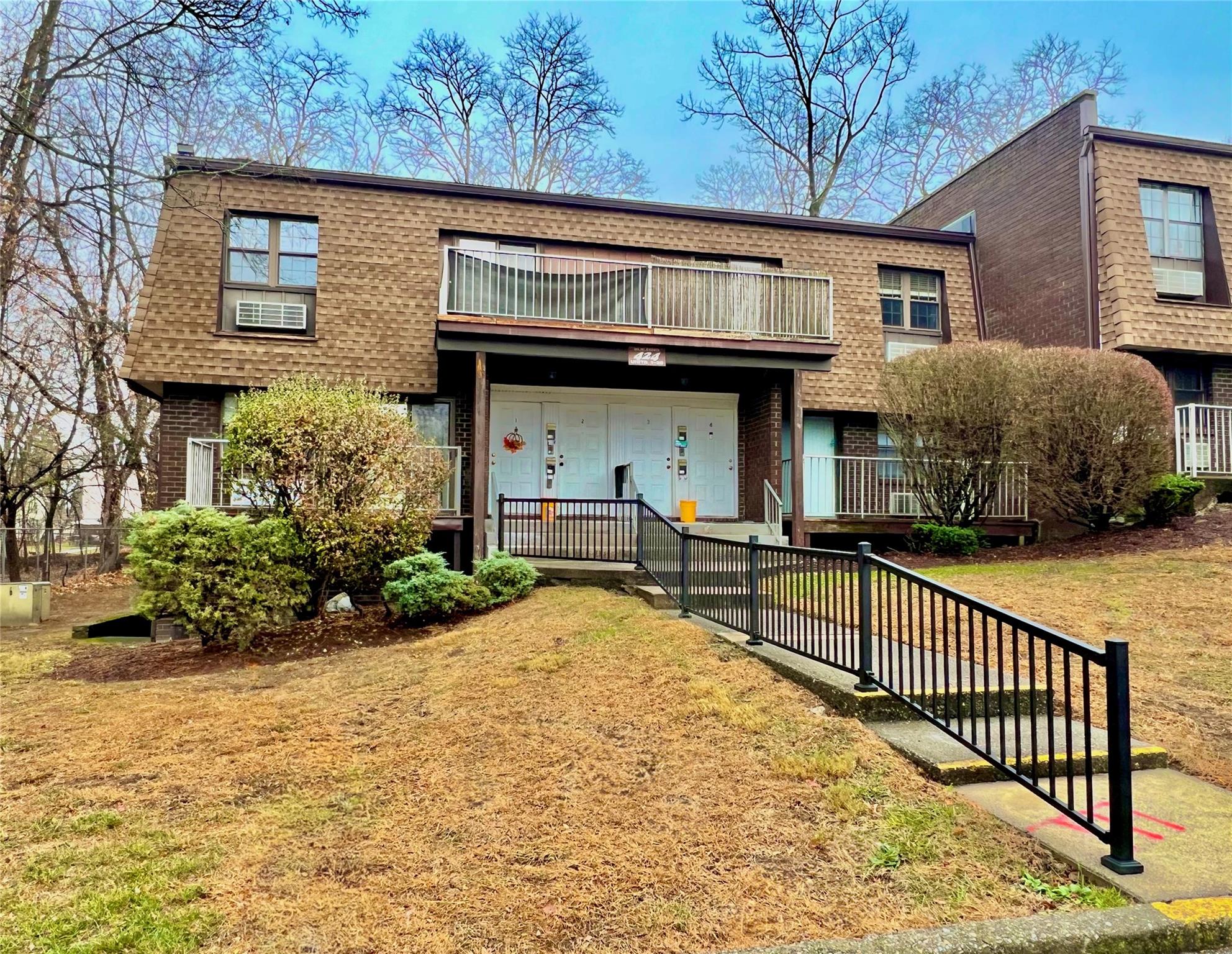 View of property with a front yard and a balcony