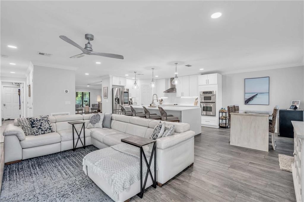 Living room featuring hardwood-style tile floors, sink, crown molding, and ceiling fan