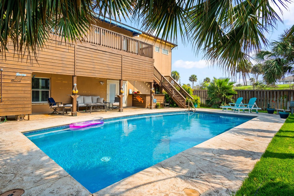 a view of swimming pool with lounge chair and palm trees