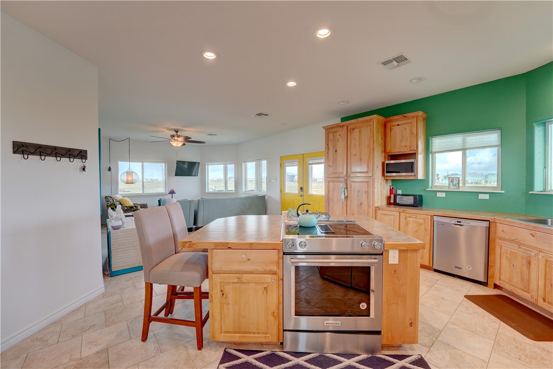 a kitchen with stainless steel appliances kitchen island granite countertop a table chairs in it and a wooden floor