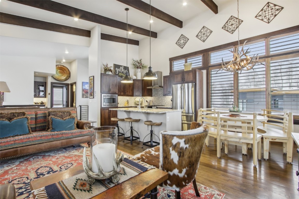 Living room featuring a high ceiling, beamed ceiling, a chandelier, and dark hardwood / wood-style flooring