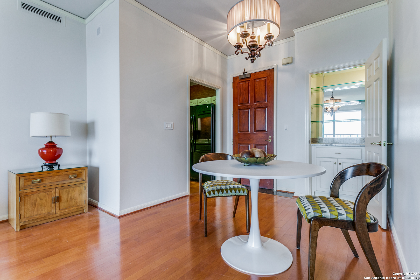 a dining room with wooden floor a chandelier a wooden table and chairs