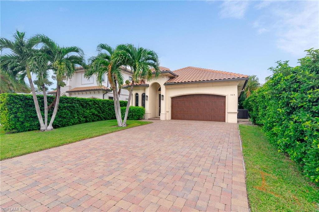 a front view of a house with a garden and palm trees