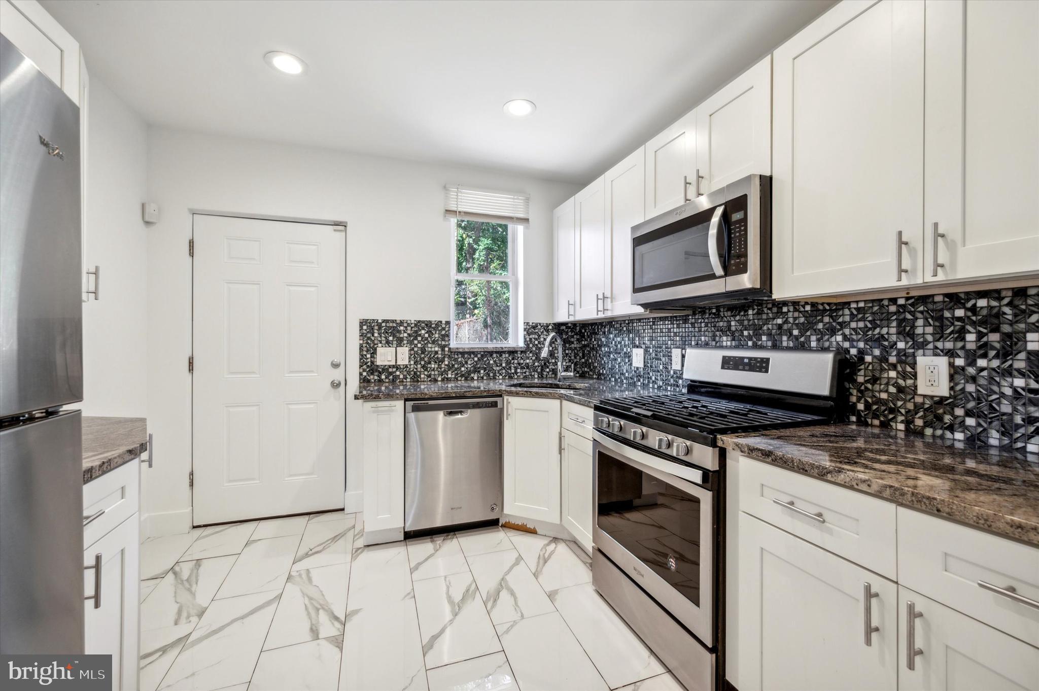 a kitchen with stainless steel appliances granite countertop a stove a sink and a microwave