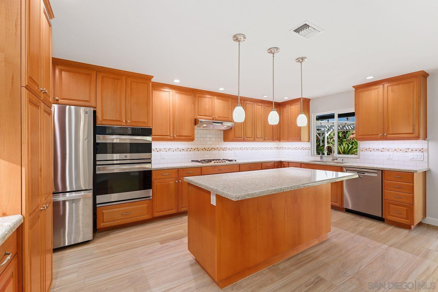 a kitchen with stainless steel appliances granite countertop a sink a stove and a wooden floors