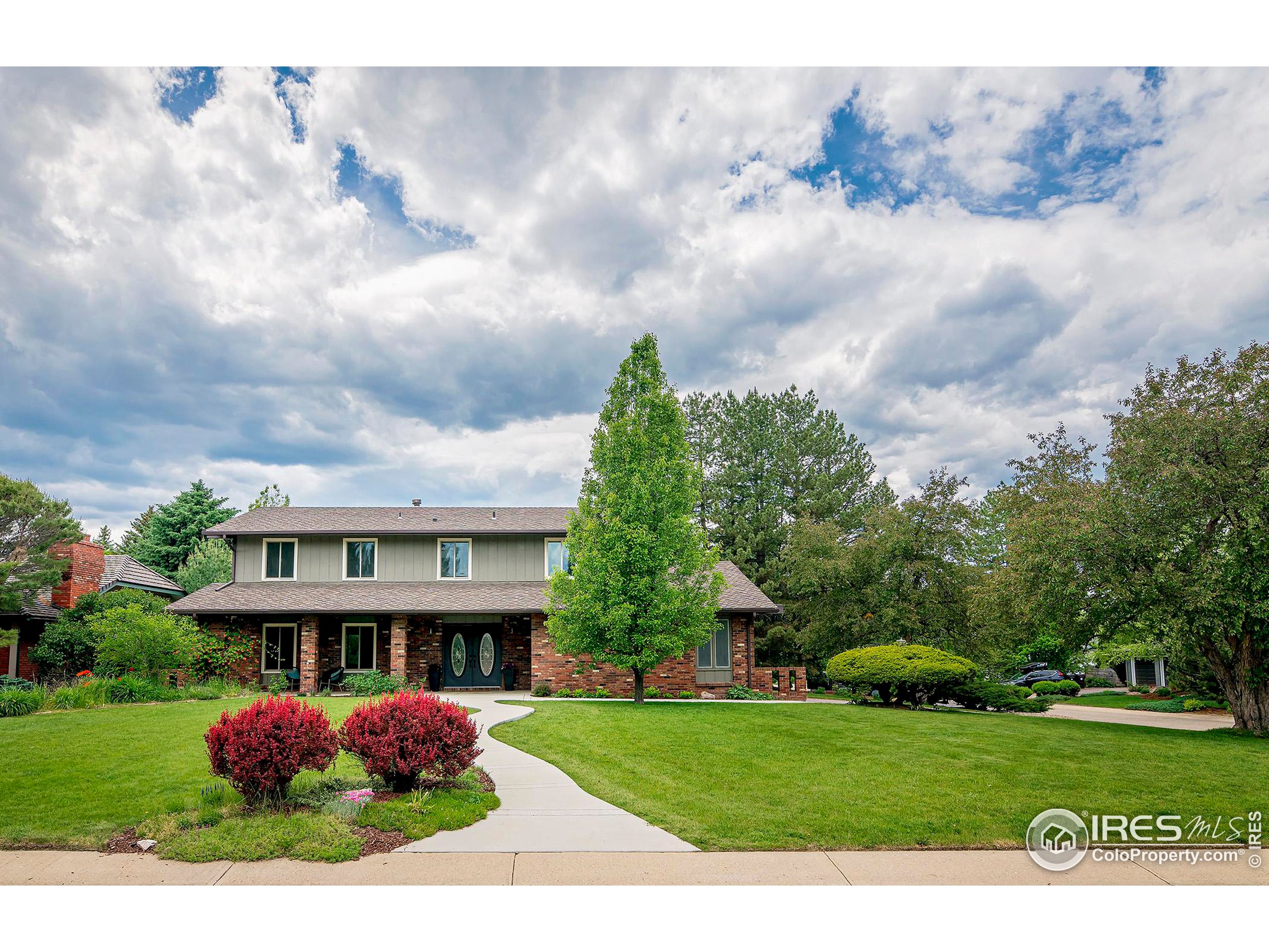 a view of a house with a big yard plants and large trees