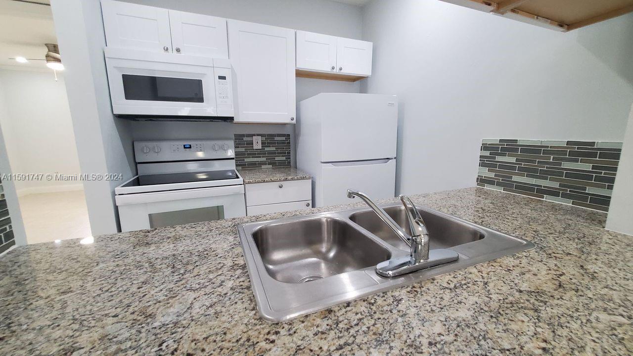 a kitchen with granite countertop a sink and a stove top oven