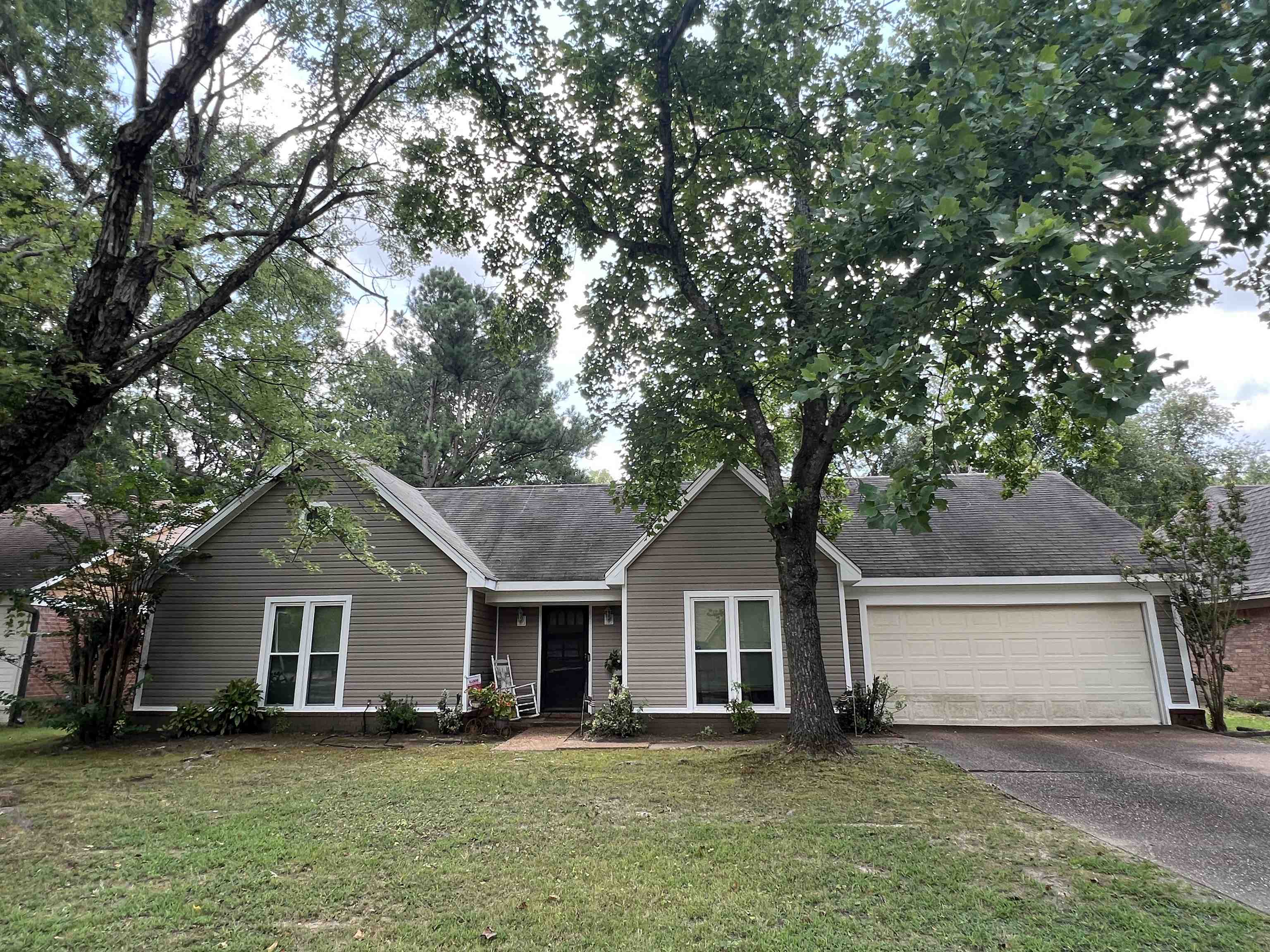 a front view of house with yard and trees in the background