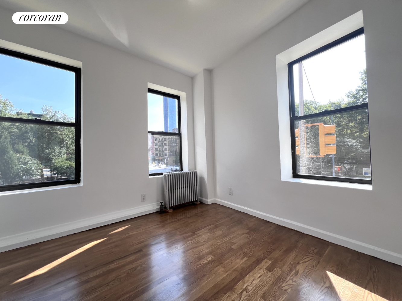 a view of an empty room with wooden floor and a window