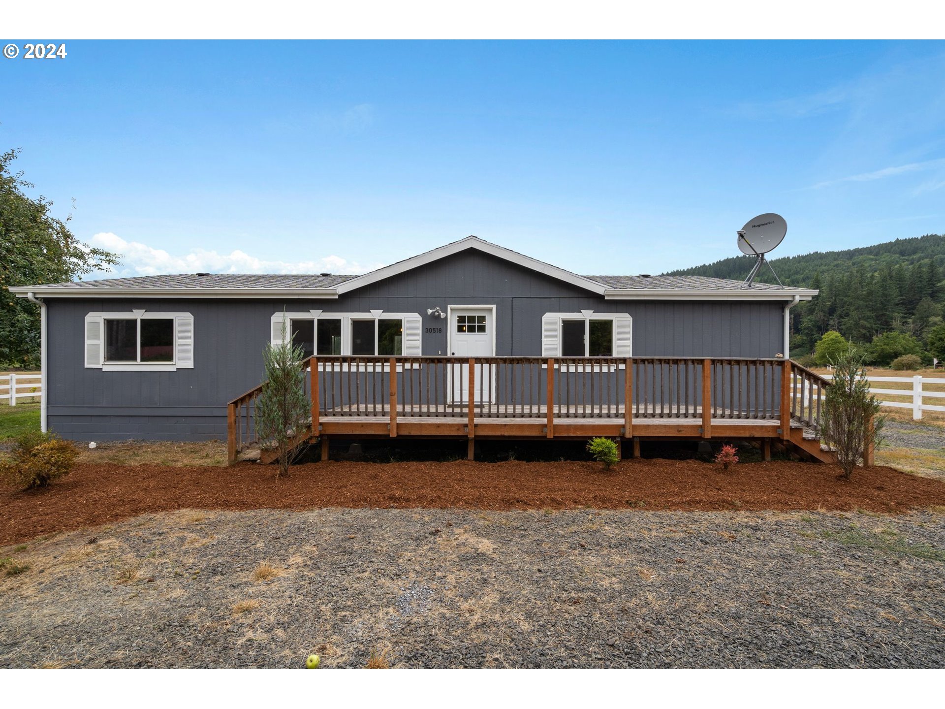 a backyard of a house with wooden deck and outdoor seating