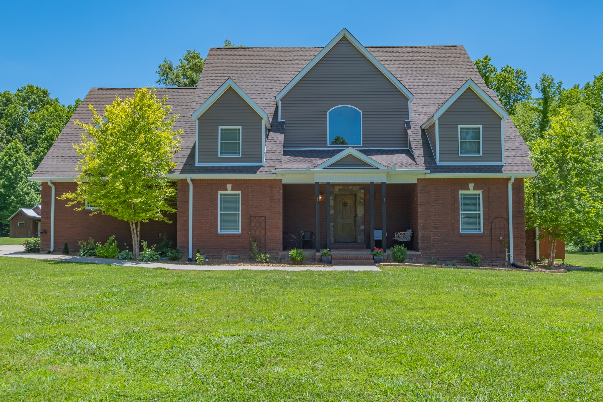 a front view of a house with a yard and trees