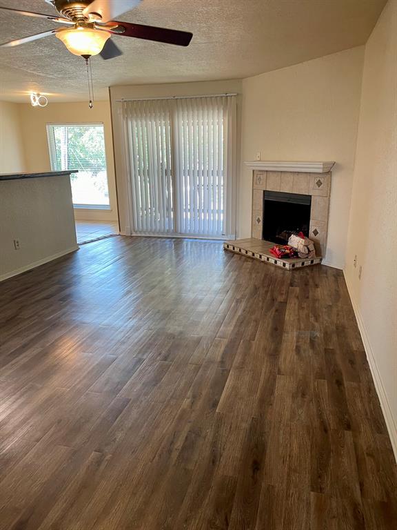 an empty room with wooden floor fireplace and windows