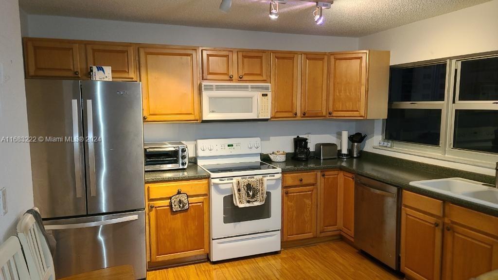 a kitchen with stainless steel appliances granite countertop a refrigerator a stove a sink and a microwave