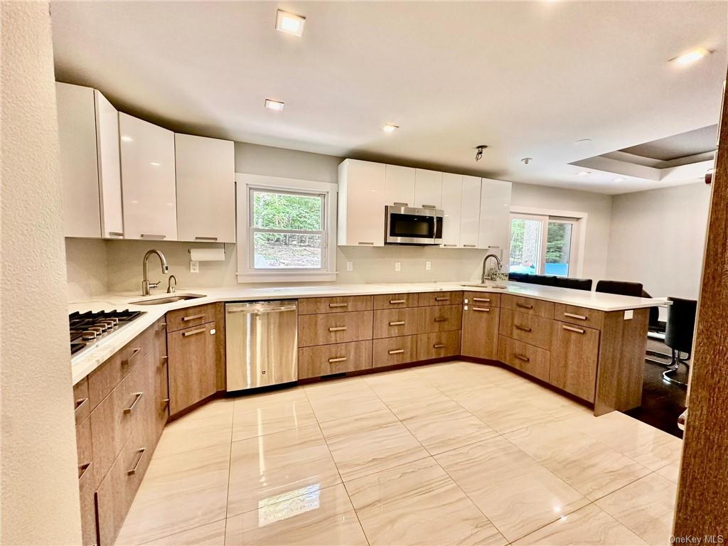 Kitchen with appliances with stainless steel finishes, a healthy amount of sunlight, sink, and white cabinets