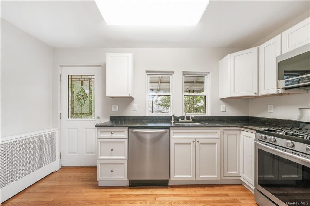 a kitchen with granite countertop a stove a sink and a microwave