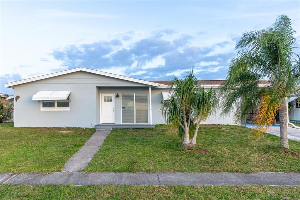 a view of a house with a yard and palm trees