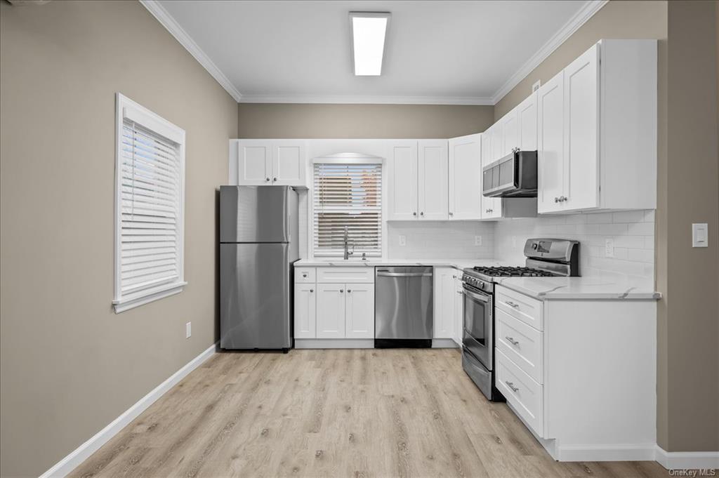 Kitchen featuring crown molding, white cabinets, light hardwood / wood-style floors, and appliances with stainless steel finishes