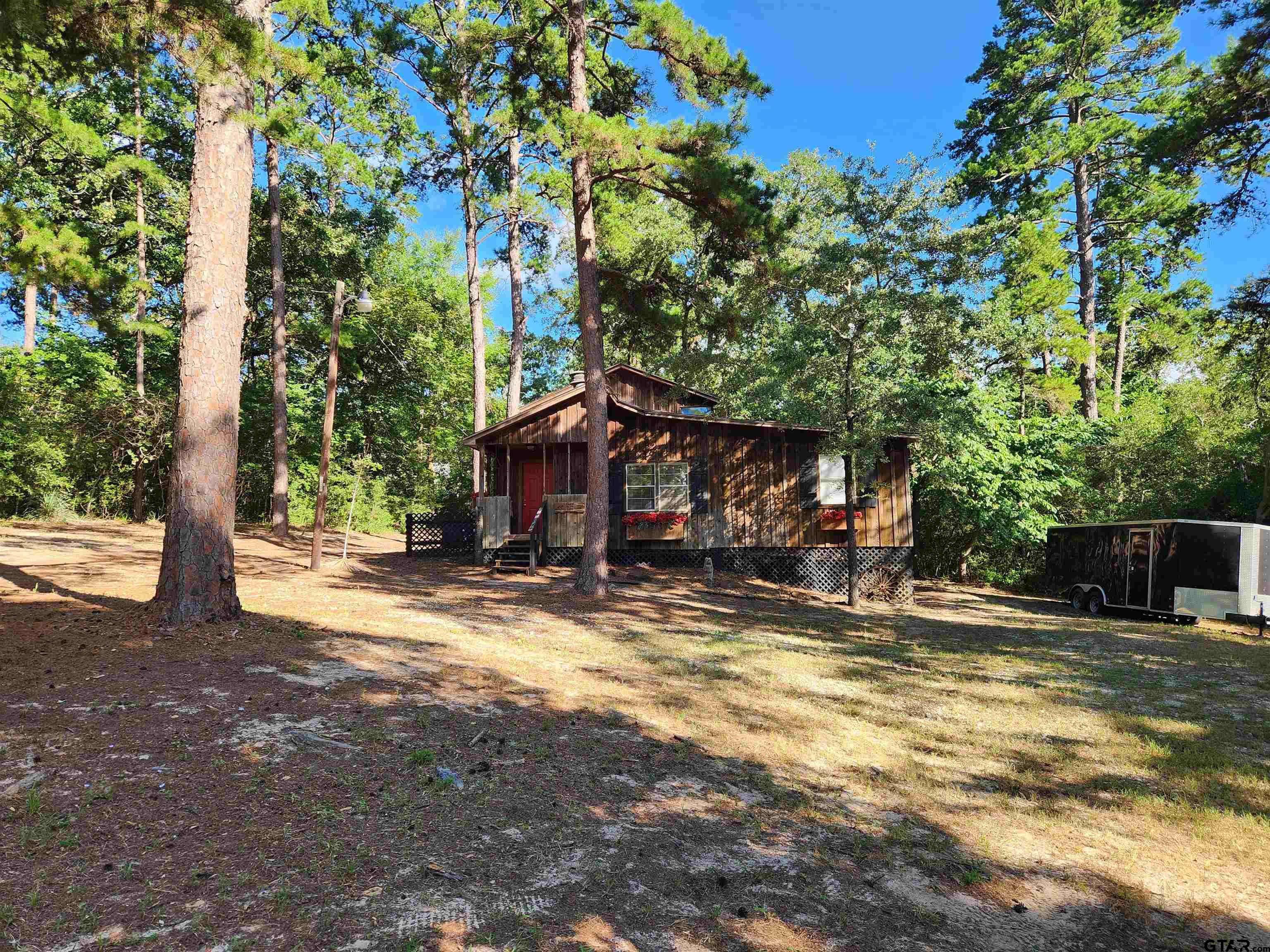 a view of a house with large tree and wooden fence